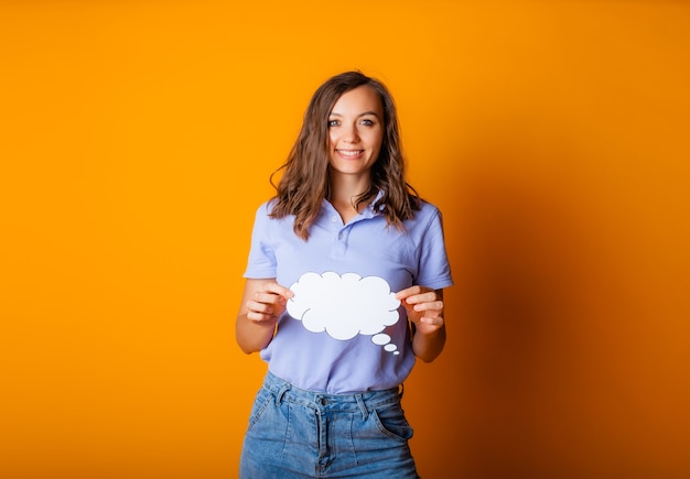 Photo happy young woman holding empty speech bubble on yellow background.