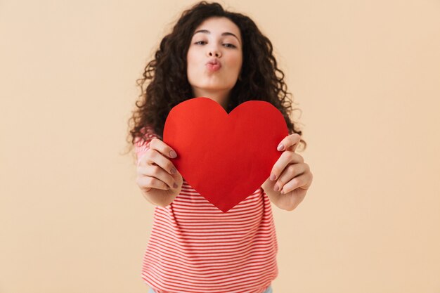Happy young woman holding heart in hands.