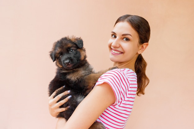 Happy young woman holding her pet puppy on orange background
