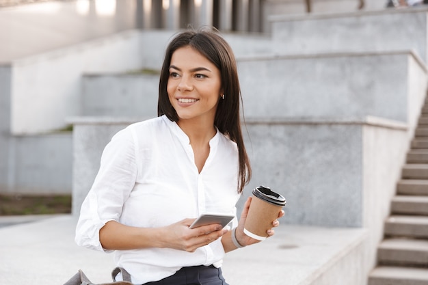 Felice giovane donna tenendo il telefono cellulare