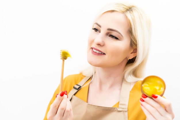 Happy young woman holding wooden bowl of honey, copy space.