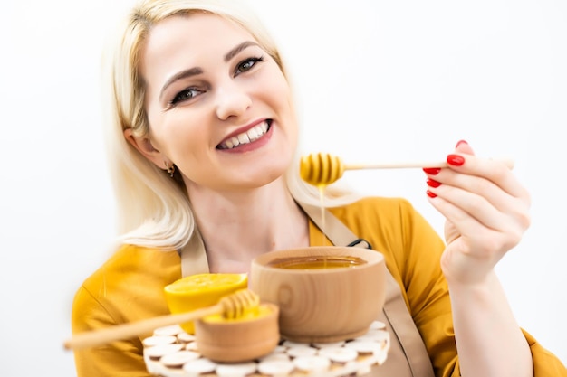 Happy young woman holding wooden bowl of honey, copy space.