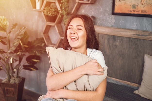 写真 幸せな若い女性が枕を抱き締める