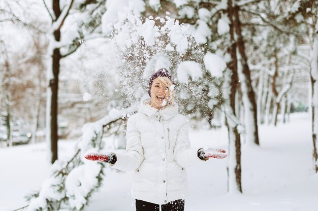 幸せな若い女性が笑って、雪で遊んでいる、冬のおかしい雰囲気。