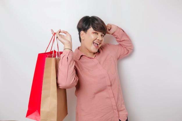 A happy young woman is wearing pink shirt and holding presents or shopping bag