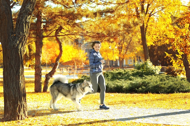公園で彼女の犬とジョギング幸せな若い女性