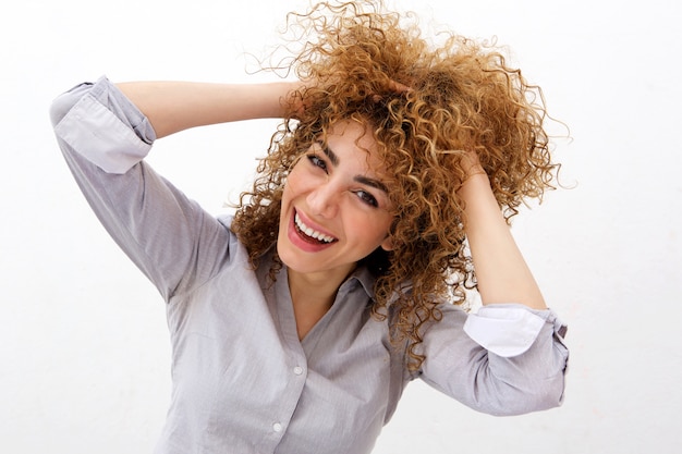 Happy young woman laughing with hand in hair against white background 