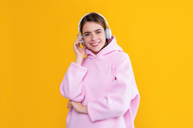 happy young woman listen music in headphones on yellow background.