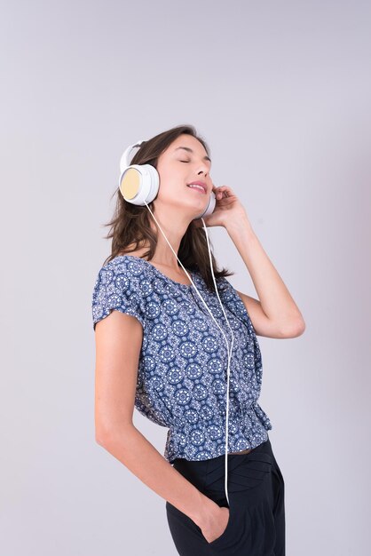 Happy young woman listening and enjoying music with headphones isolated on a white background