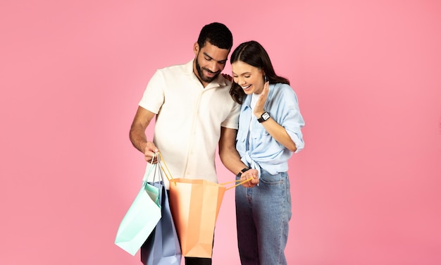 Photo happy young woman looking inside paper bag shopping with boyfriend