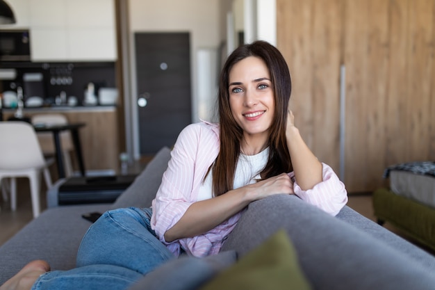 Photo happy young woman lying on couch and relaxing at home