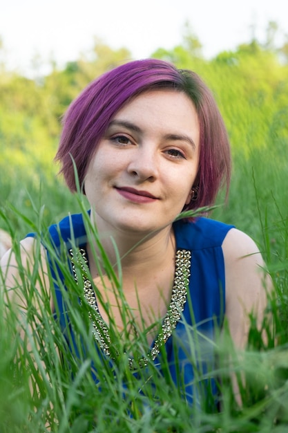 Photo happy young woman lying in grass in nature in summer