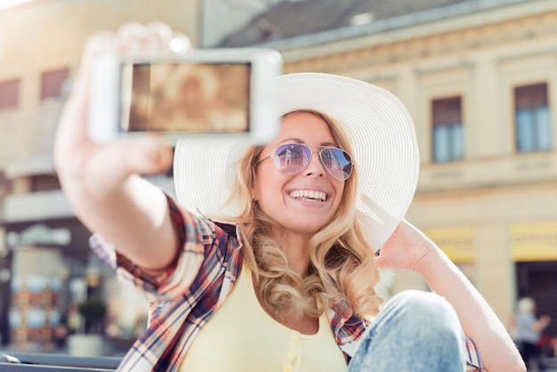 Foto felice giovane donna che fa selfie in città.