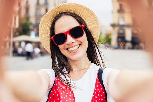 Foto felice giovane donna che fa selfie con lo smartphone nella strada della città - turista gioiosa che si diverte durante le vacanze a barcellona - vacanze estive e concetto di stile di vita felice