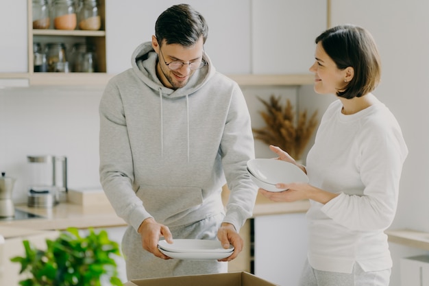 Happy young woman and man open boxes with dishes