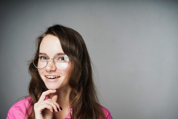 Felice giovane donna impiegata in una camicia rosa e occhiali sorridenti