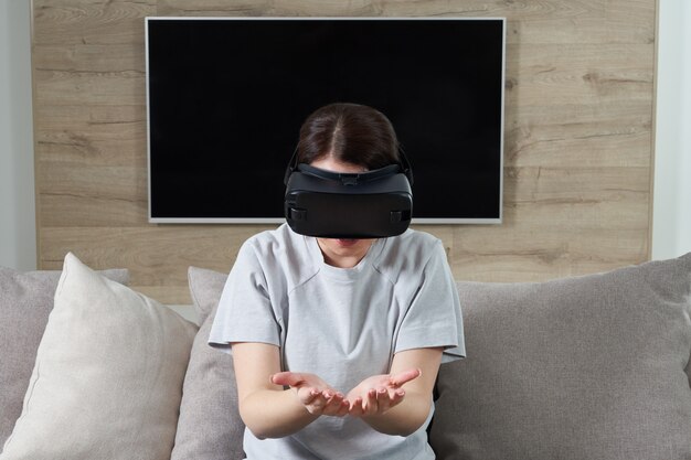 屋内VRメガネで遊んで幸せな若い女、ヘッドセットゴーグルを楽しんでいる若い女の子と仮想現実の概念