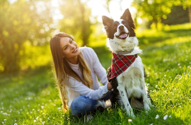 屋外の公園で彼女の犬と遊ぶ幸せな若い女性