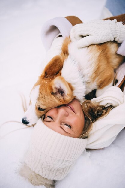 Happy young woman playing with her welsh corgi pembroke puppy winter forest