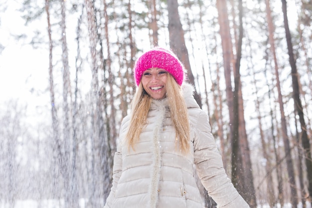 Happy young woman plays with a snow at snowy forest outdoor.