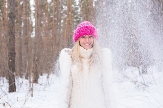 La giovane donna felice gioca con una neve al bosco innevato all'aperto.