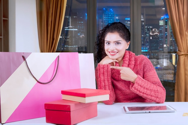 Happy young woman pointing shopping bags
