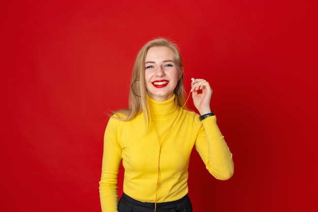 노란 스웨터를 입고 빨간색 배경에 행복 한 젊은 여자