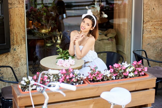 Фото Счастливая молодая женщина, отдыхая в кафе на открытом воздухе