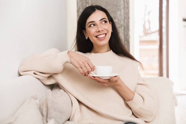 Happy young woman relaxing on a couch at the living room