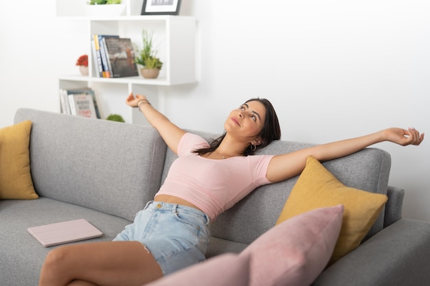 Happy young woman resting with her arms outstretched on the couch