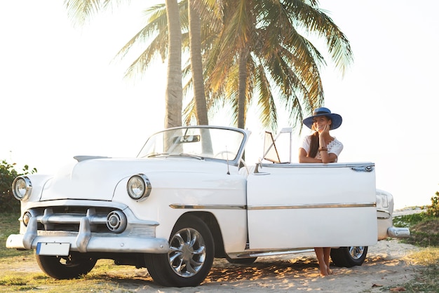 Happy young woman and retro convertible car beside the beach at Varadero city
