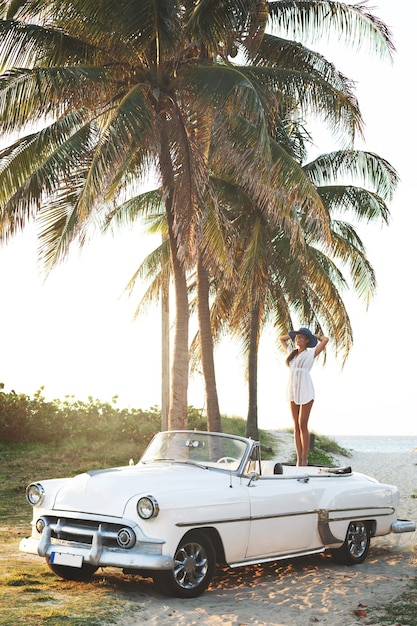 Happy young woman and retro convertible car beside the beach at Varadero city