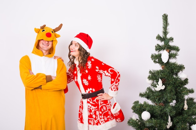 Happy young woman in santa claus hat and man in carnival costume of deer.