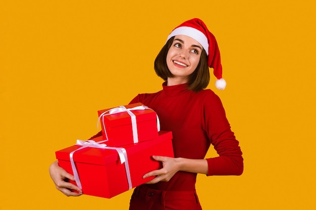 クリスマス プレゼントを保持しているサンタ帽子で幸せな若い女