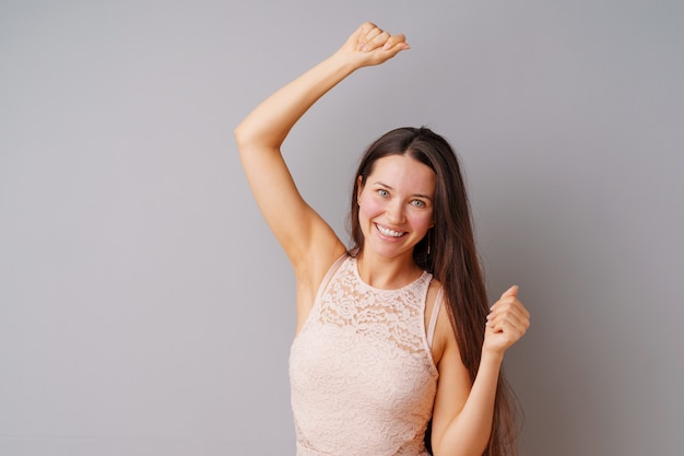 Happy young woman showing her victory  over gray background