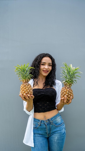 Happy young woman showing pineapple pineapple fruit woman\
smiling healthy and joyful mixedrace asian caucasian model with\
pineapple