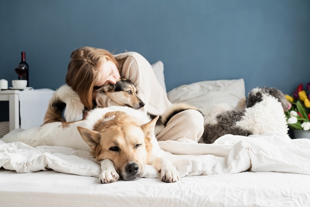 彼女の犬、青い壁の背景、犬に焦点を当ててベッドに座っている幸せな若い女性