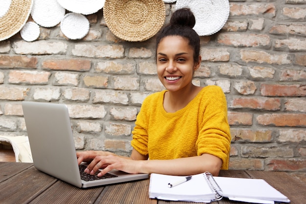 Happy young woman sitting at cafe with laptop