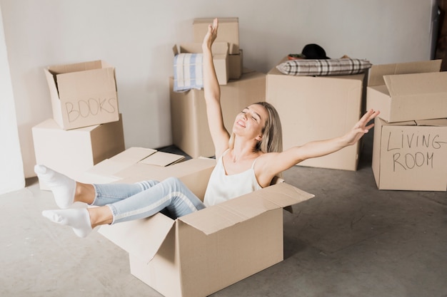 Happy young woman sitting in carton box