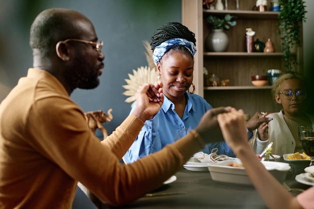 Photo happy young woman sitting between her husband and daughter and holding by their hands