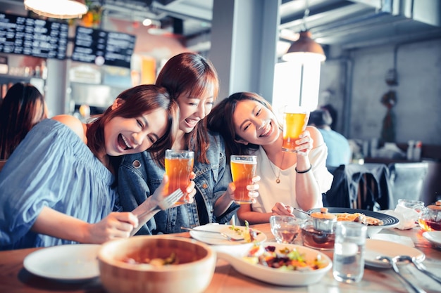 レストランに座ってディナーとビールを楽しむ幸せな若い女性