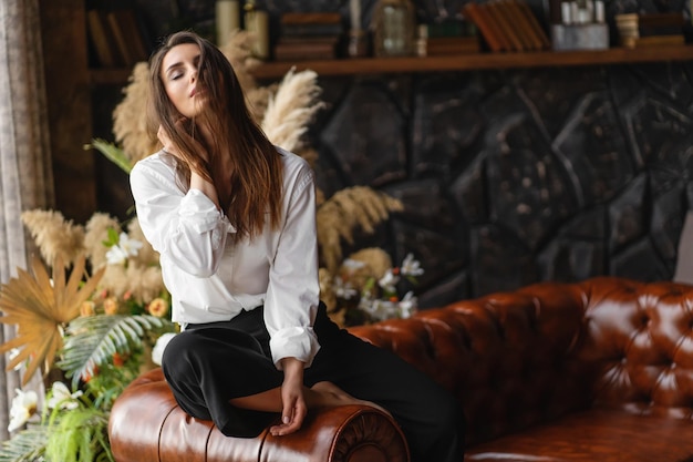 Happy young woman sitting on sofa at home with closed eyes