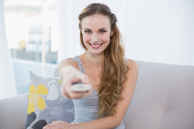 Photo happy young woman sitting on sofa watching tv