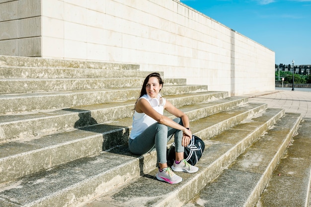 Photo happy young woman sitting on stairs outdoors after workout session