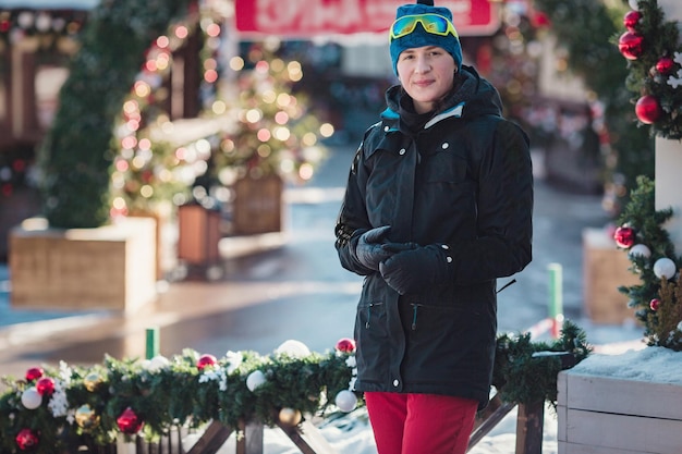 Happy young woman in ski goggles outdoors winter vacation concept Christmas decorations in a small ski resort Rest after successful skiing competition