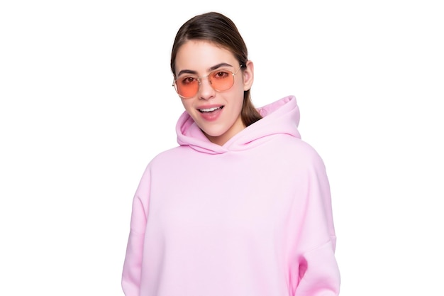 Счастливая молодая женщина улыбается в повседневной розовой толстовке с капюшоном и очках, изолированных от белой девушки