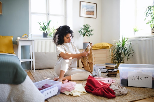 幸せな若い女性が自宅でワードローブを並べ替え、チャリティー寄付の概念。