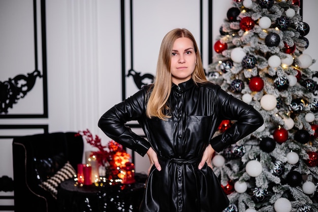 Happy young woman spending christmas holidays at home smiling broadly against decorated christmas tree and garland