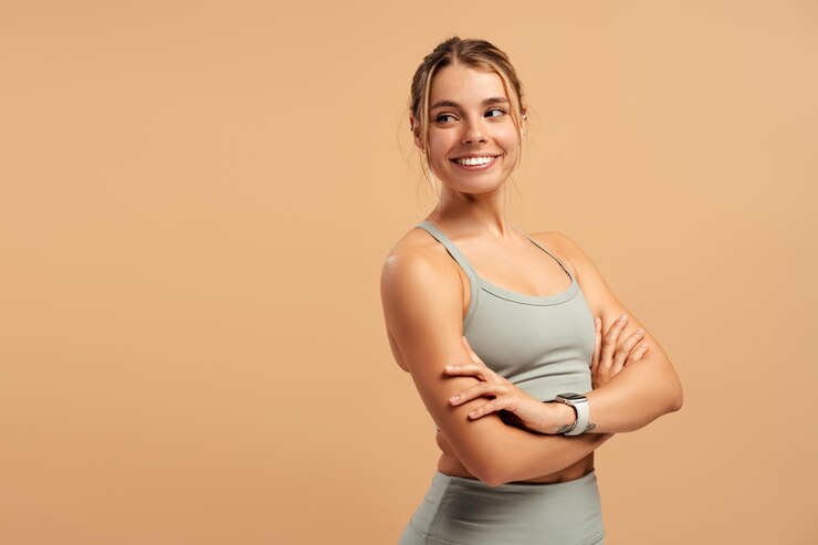 Photo happy young woman in sportwear holding hands crossed folding isolated on beige in studio