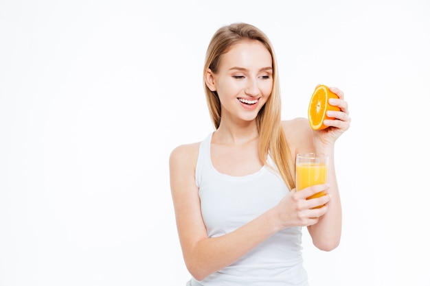 Happy young woman squeezes orange in juice isolated on a white background